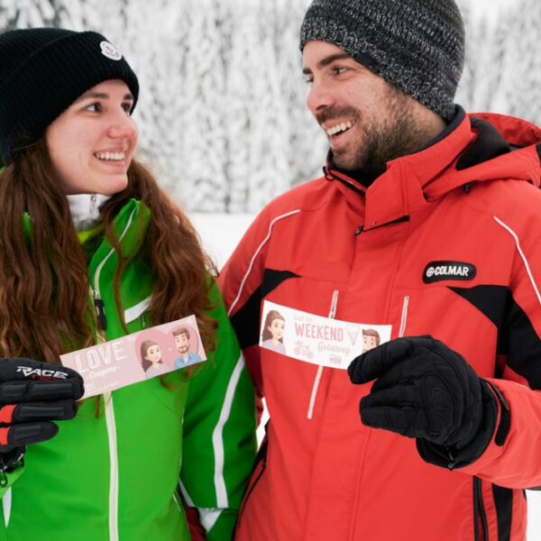 A couple in the snow holding Hooray Heroes personalised love coupons.
