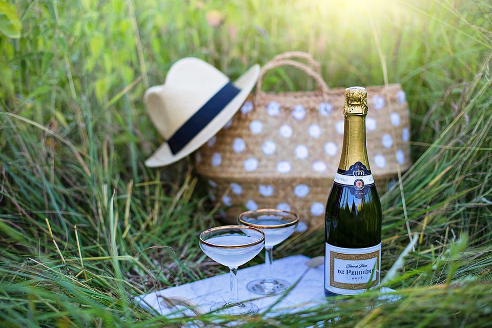 A picnic in a field with champagne and a basket.