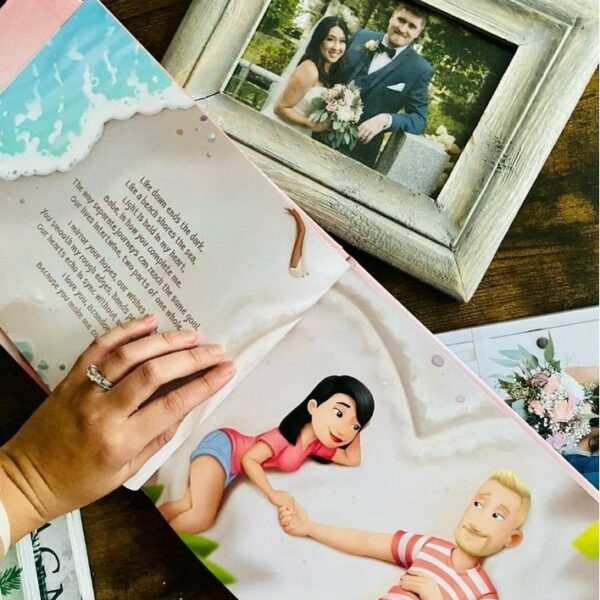 A woman's hand holds open a personalised love you book next to her wedding photo.